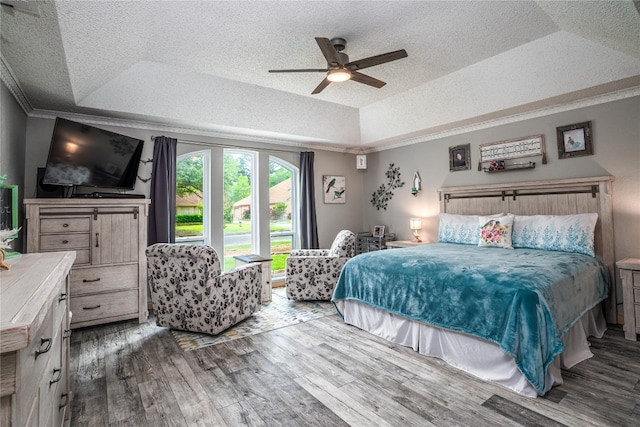 bedroom with ceiling fan, a textured ceiling, dark hardwood / wood-style floors, and a raised ceiling