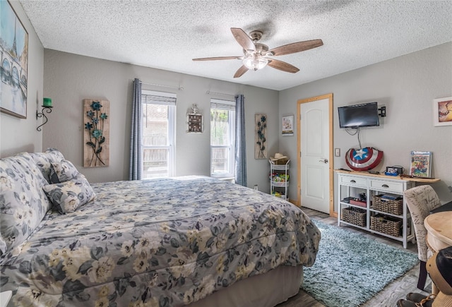 bedroom with a textured ceiling, wood-type flooring, and ceiling fan