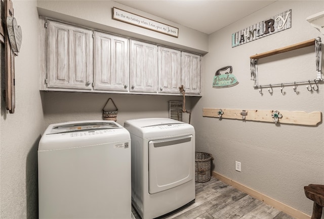 clothes washing area with cabinets, light hardwood / wood-style flooring, and independent washer and dryer