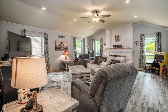 living room with lofted ceiling, ornamental molding, ceiling fan, and light wood-type flooring