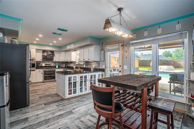 dining space featuring sink, crown molding, a healthy amount of sunlight, and light hardwood / wood-style flooring