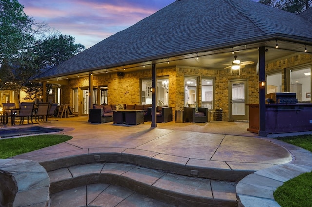 back house at dusk featuring ceiling fan, a patio, and an outdoor hangout area