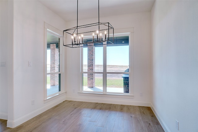 unfurnished dining area with a chandelier and light wood-type flooring