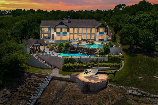 back house at dusk with a patio and a fenced in pool