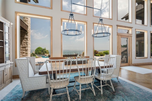 dining room with a towering ceiling, light hardwood / wood-style floors, a wealth of natural light, and a chandelier