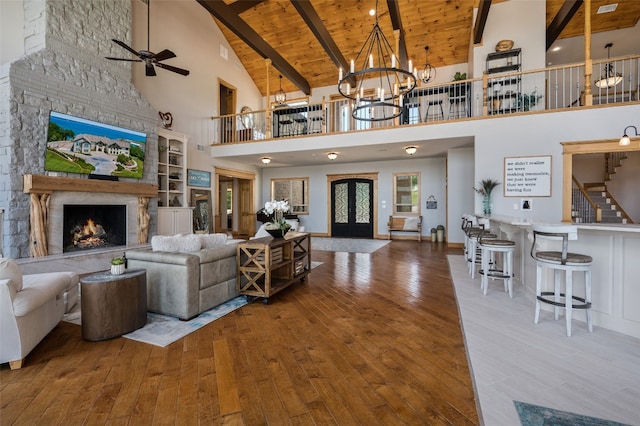 living room featuring beam ceiling, a stone fireplace, high vaulted ceiling, wood ceiling, and french doors