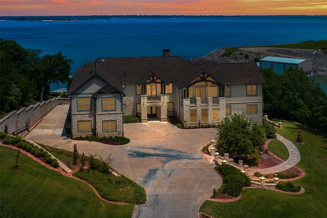 view of front of home with a yard, a balcony, and a water view