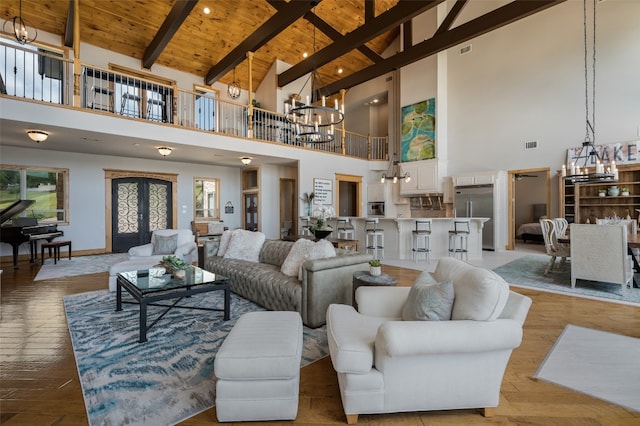 living room featuring high vaulted ceiling, wooden ceiling, french doors, beamed ceiling, and an inviting chandelier