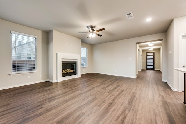 unfurnished living room with dark hardwood / wood-style flooring and ceiling fan