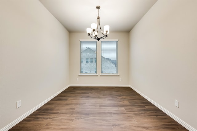 unfurnished dining area featuring dark wood-type flooring and a chandelier