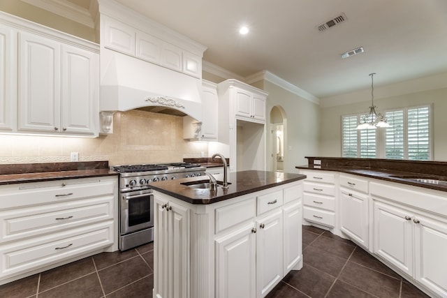 kitchen featuring tasteful backsplash, custom exhaust hood, white cabinetry, a chandelier, and stainless steel range