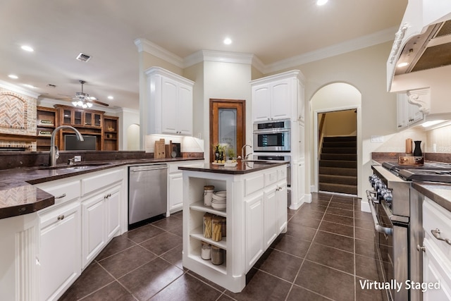 kitchen featuring ceiling fan, appliances with stainless steel finishes, dark tile floors, white cabinets, and ornamental molding