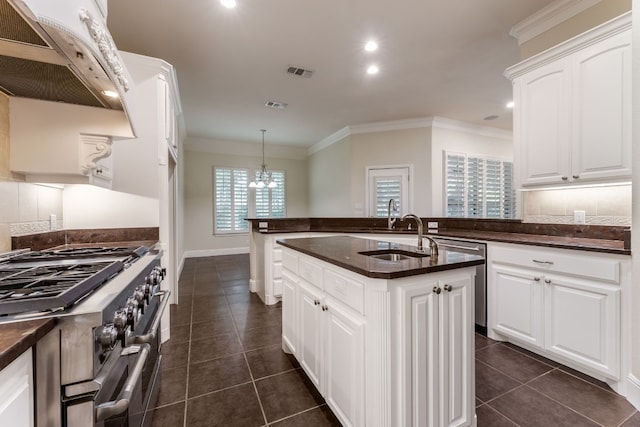 kitchen featuring a chandelier, pendant lighting, stainless steel stove, a center island with sink, and white cabinets