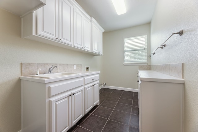 washroom featuring dark tile flooring, washer hookup, cabinets, and sink