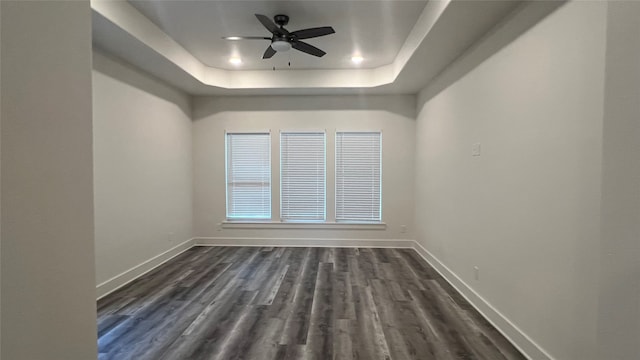 unfurnished room with dark hardwood / wood-style flooring, ceiling fan, and a raised ceiling