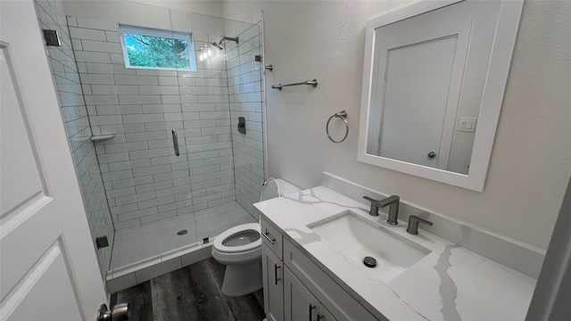 bathroom with a shower with door, hardwood / wood-style floors, vanity, and toilet