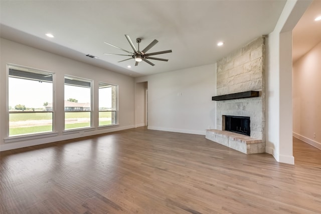 unfurnished living room with ceiling fan, a fireplace, and light hardwood / wood-style flooring