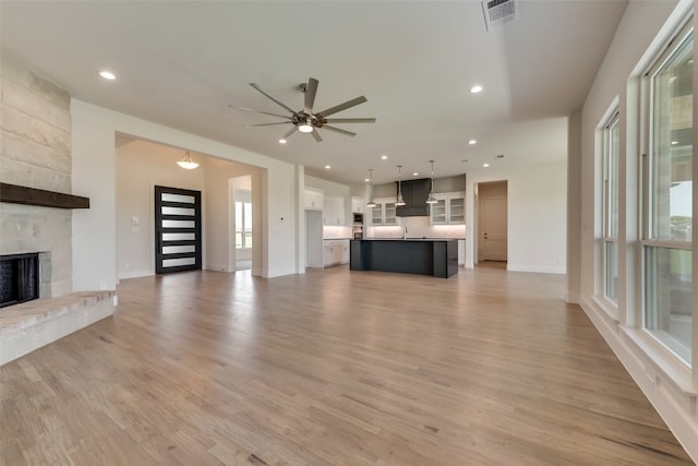 unfurnished living room featuring ceiling fan, a fireplace, and light hardwood / wood-style floors