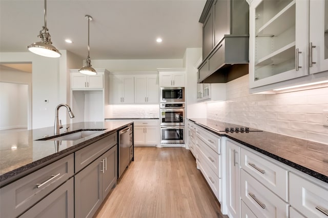 kitchen featuring white cabinetry, sink, hanging light fixtures, dark stone countertops, and appliances with stainless steel finishes