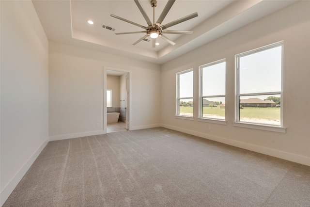 carpeted spare room featuring a tray ceiling and ceiling fan