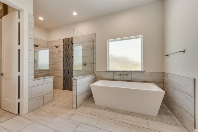 bathroom featuring plus walk in shower and tile walls