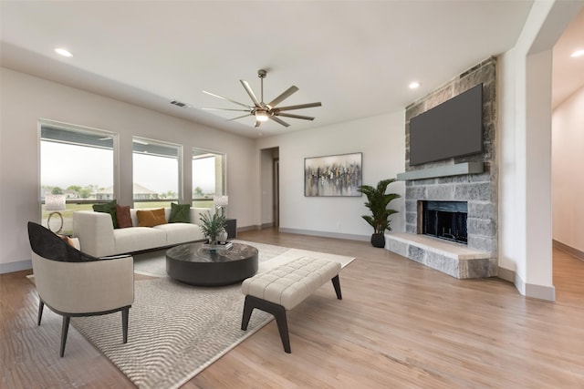 living room with a fireplace, light wood-type flooring, and ceiling fan