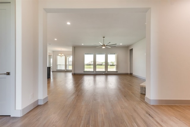 interior space featuring ceiling fan with notable chandelier and light wood-type flooring