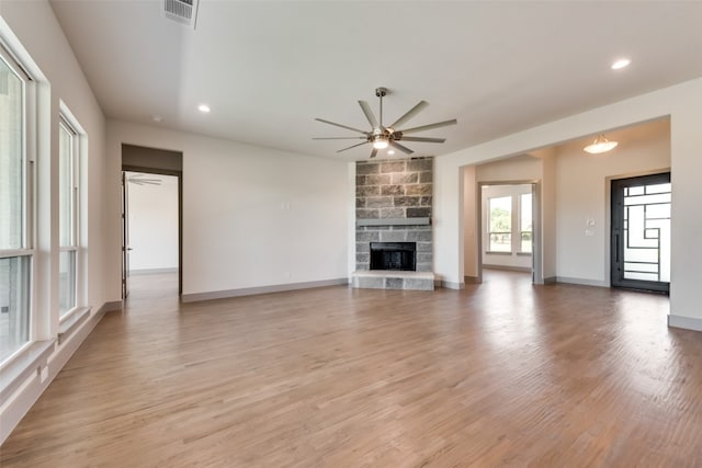 unfurnished living room with a fireplace, light wood-type flooring, and ceiling fan