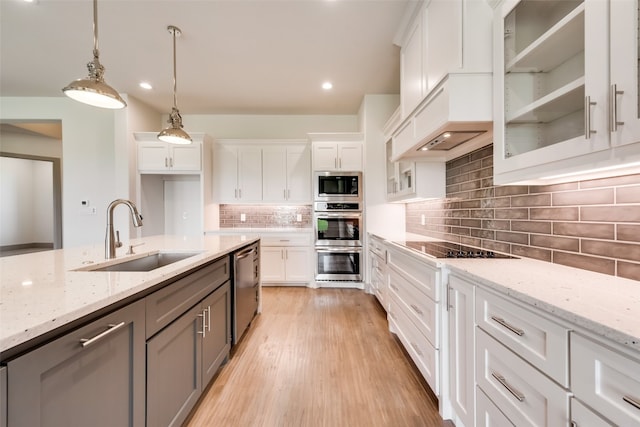 kitchen featuring sink, stainless steel appliances, hanging light fixtures, light stone counters, and white cabinets