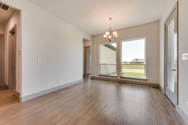 interior space featuring a chandelier, light wood-type flooring, and a healthy amount of sunlight