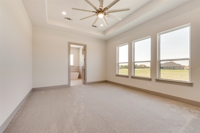 carpeted spare room featuring ceiling fan and a tray ceiling