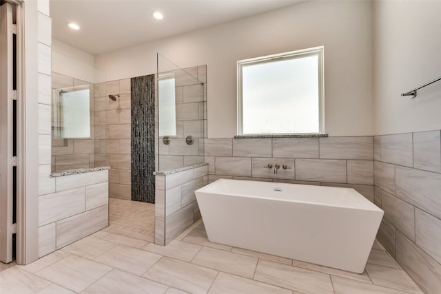 bathroom featuring tile walls and independent shower and bath