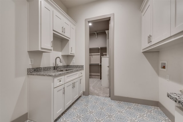 kitchen featuring white cabinets, light stone countertops, and sink