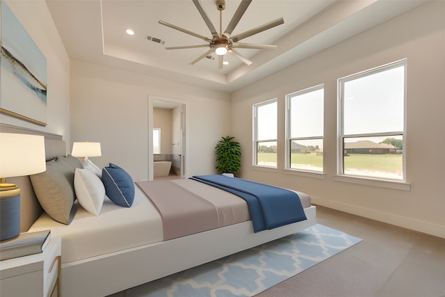 bedroom with a raised ceiling, connected bathroom, ceiling fan, and light colored carpet