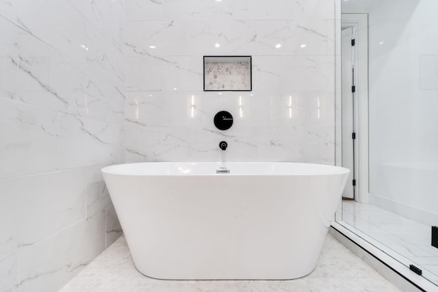 bathroom with a tub and tile walls