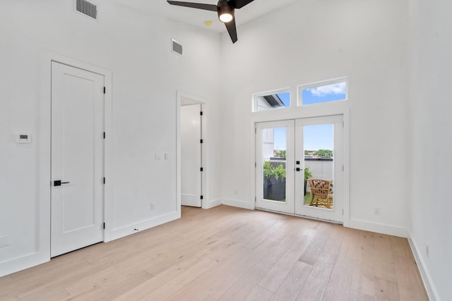 spare room with ceiling fan, french doors, a high ceiling, and light hardwood / wood-style flooring