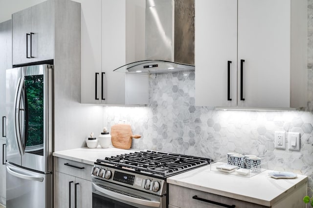 kitchen with backsplash, wall chimney exhaust hood, light stone counters, and stainless steel appliances