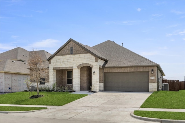 french country inspired facade featuring a front yard, a garage, and central air condition unit