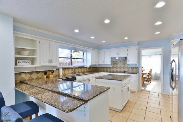 kitchen featuring backsplash, a kitchen breakfast bar, stainless steel refrigerator, and white cabinetry