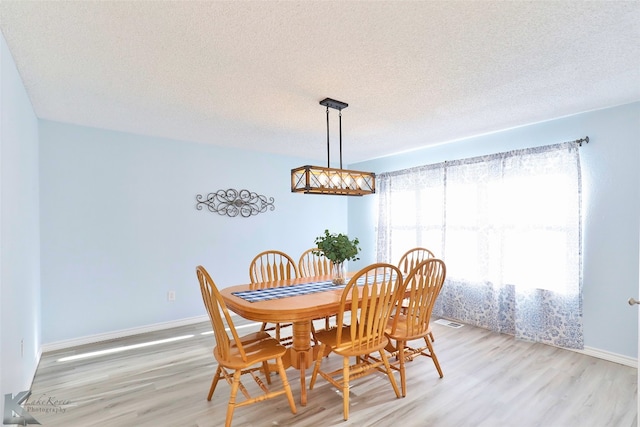 dining area with light hardwood / wood-style flooring and a textured ceiling