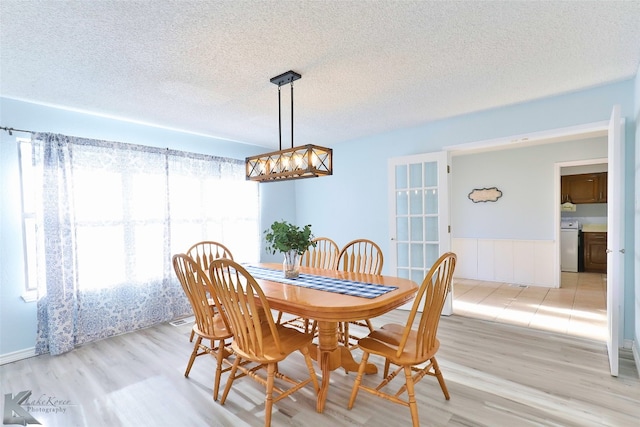 tiled dining space featuring a textured ceiling and washer / dryer