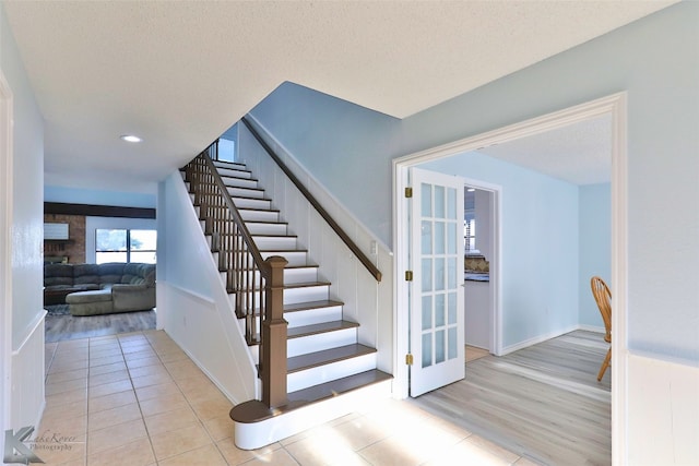 stairway with light tile flooring, a textured ceiling, and a fireplace