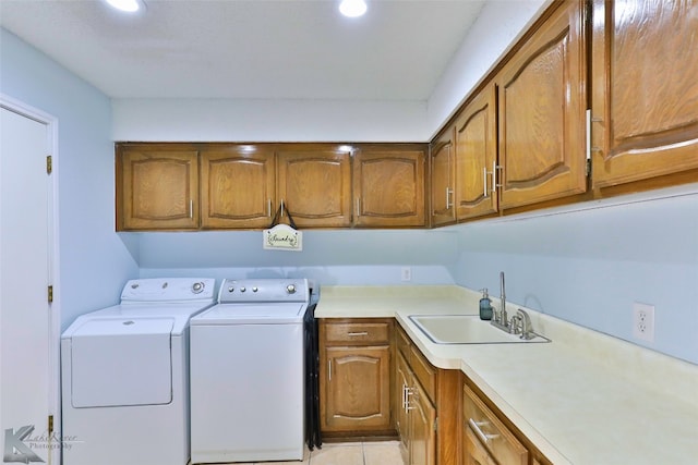 clothes washing area with cabinets, sink, light tile floors, and washer and dryer