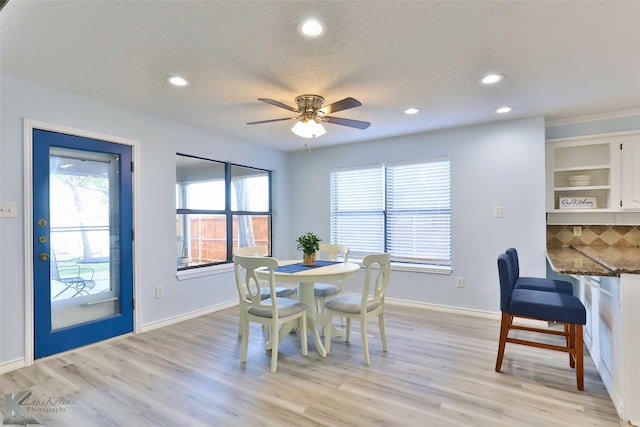 dining area with ceiling fan, built in shelves, light wood-type flooring, and a textured ceiling