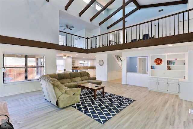 living room featuring beamed ceiling, high vaulted ceiling, ceiling fan, and light hardwood / wood-style flooring