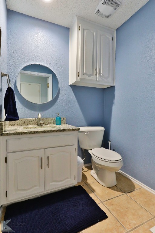 bathroom featuring toilet, tile flooring, a textured ceiling, and vanity