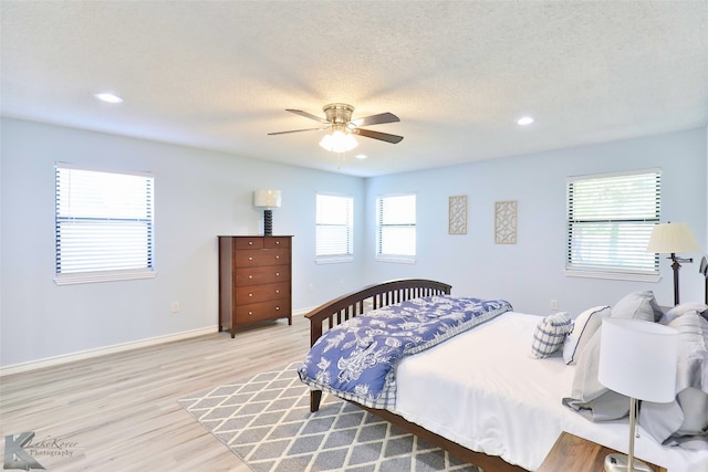 bedroom with a textured ceiling, ceiling fan, and light wood-type flooring