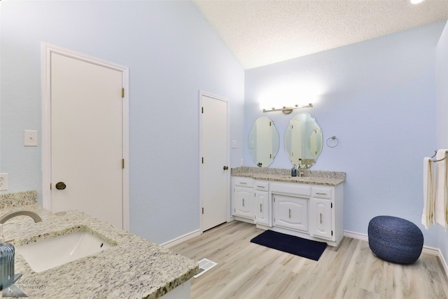 bathroom featuring vanity, a textured ceiling, vaulted ceiling, and hardwood / wood-style flooring