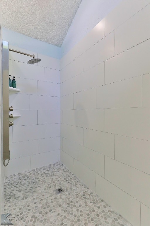 bathroom with lofted ceiling and tiled shower