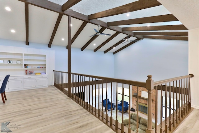 hallway featuring vaulted ceiling with beams, light hardwood / wood-style flooring, a textured ceiling, and built in shelves